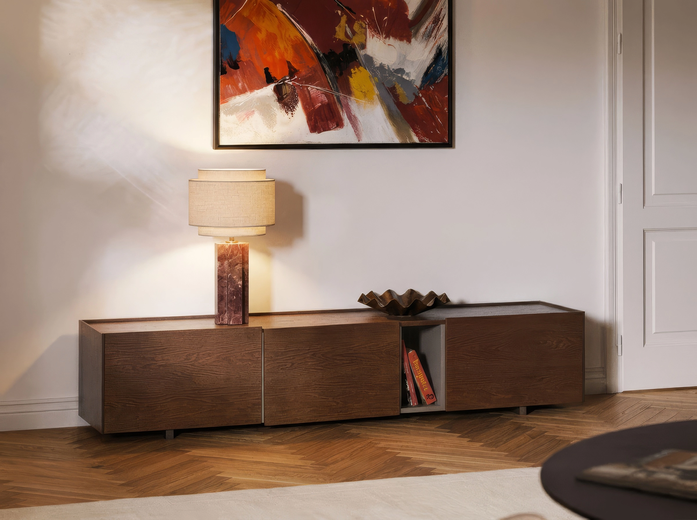 Lampe en marbre rouge sur un buffet en noyer, sous un tableau abstrait